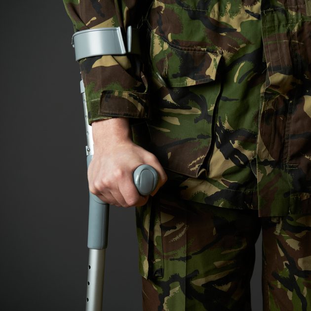 Studio Shot Of Wounded Soldier Using Crutch